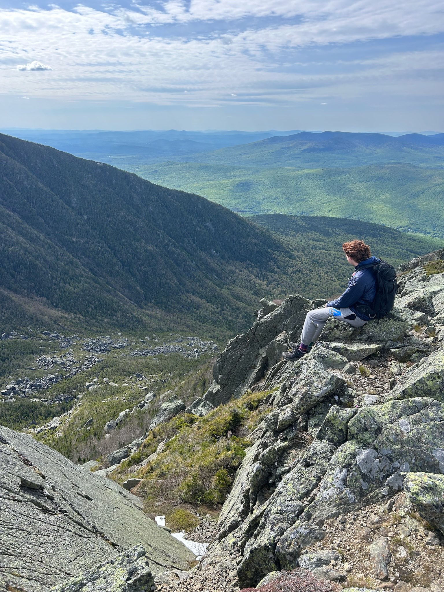 Logan sitting on a mountain with a wide valley view